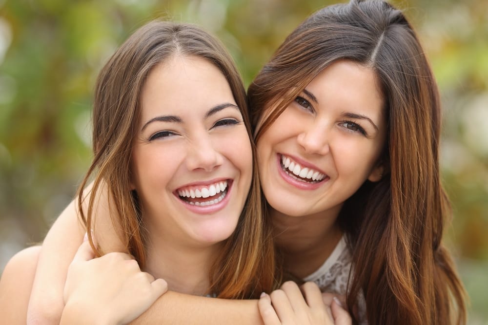 Two women friends laughing with a perfect white teeth - Dental Implants in Columbus, Ohio