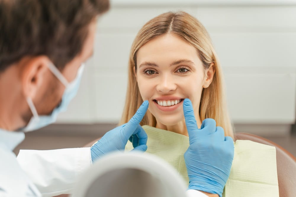 A dentist points at a smiling woman's teeth during a checkup - Dentist Columbus Ohio​​ 